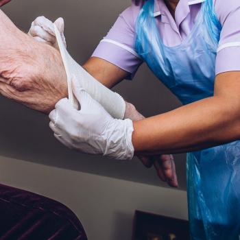 woman placing bandage on a senior man's arm