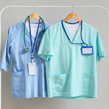 Two Healthcare uniforms hanging from a coat rack.